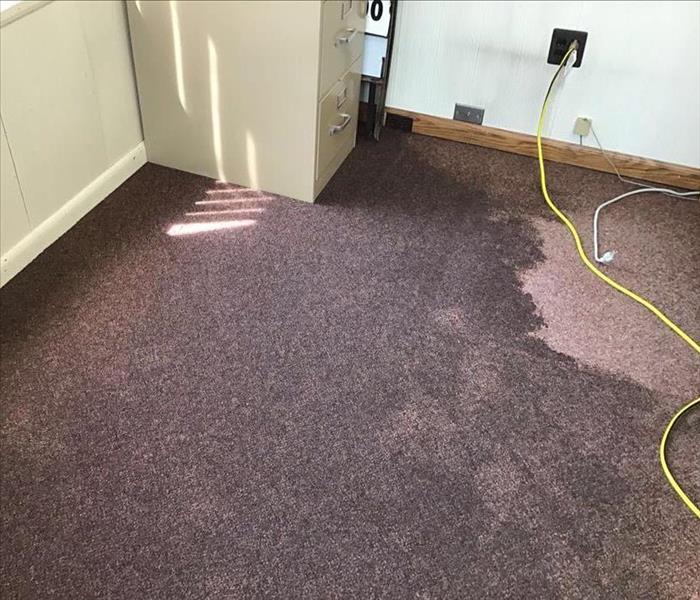 water on the floor of carpet, file cabinet nearby, tube in wall outlet