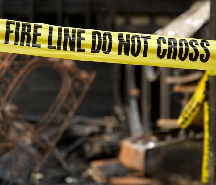 Yellow tape with the words " fire line do not cross in front of a burnt home.