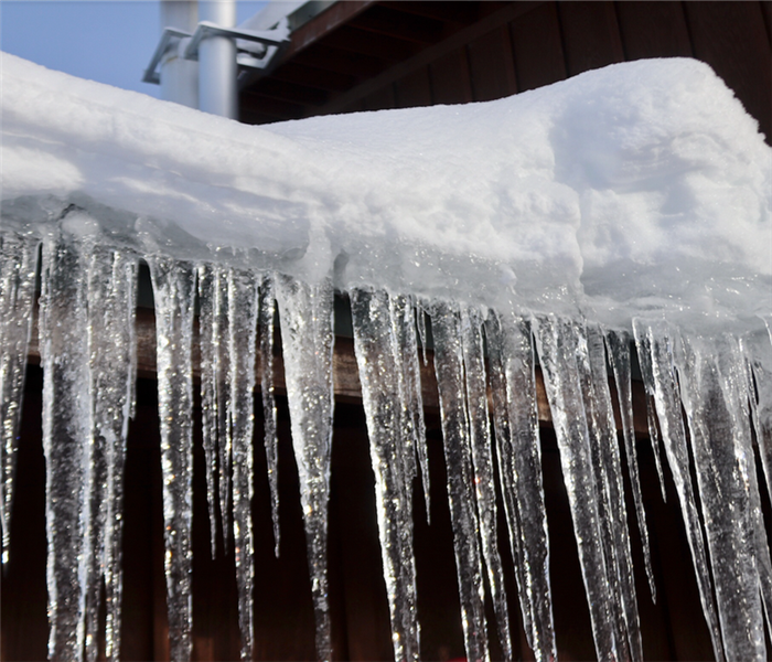 icicles hanging off of the roof of a house by the pipes